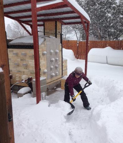 Nicole shoveling snow in front of her kiln.